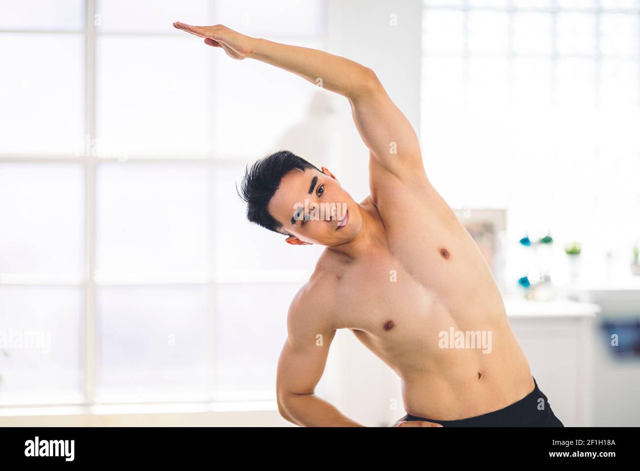 Muscular Asian young man doing  exercises at home Stock Photo