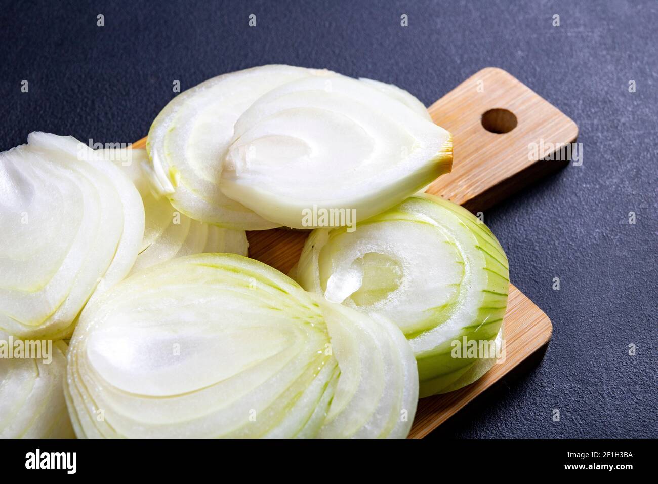 Sliced onion placed on a wooden board. Vegetables in the kitchen prepared  to serve. Dark background Stock Photo - Alamy