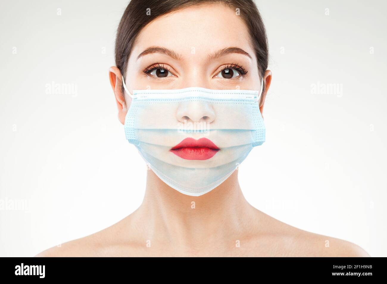 Beautiful caucasian young woman headshot,wearing transparent medical face mask,COVID-19 new normal concept,creative edit showing red lips Stock Photo