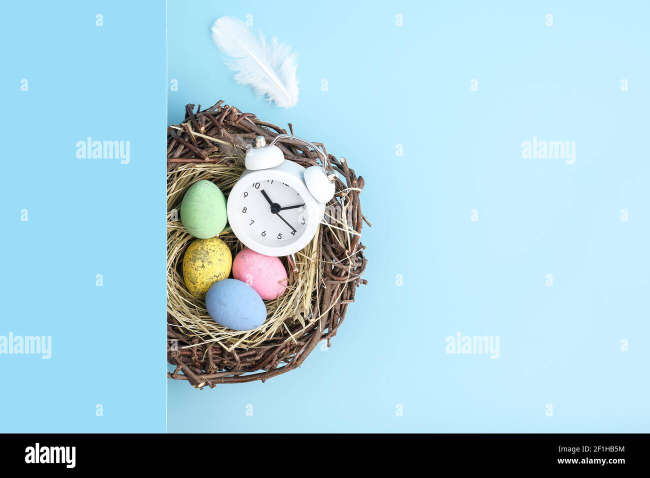 Top view of alarm clock, easter eggs and nest flatlay. Stock Photo