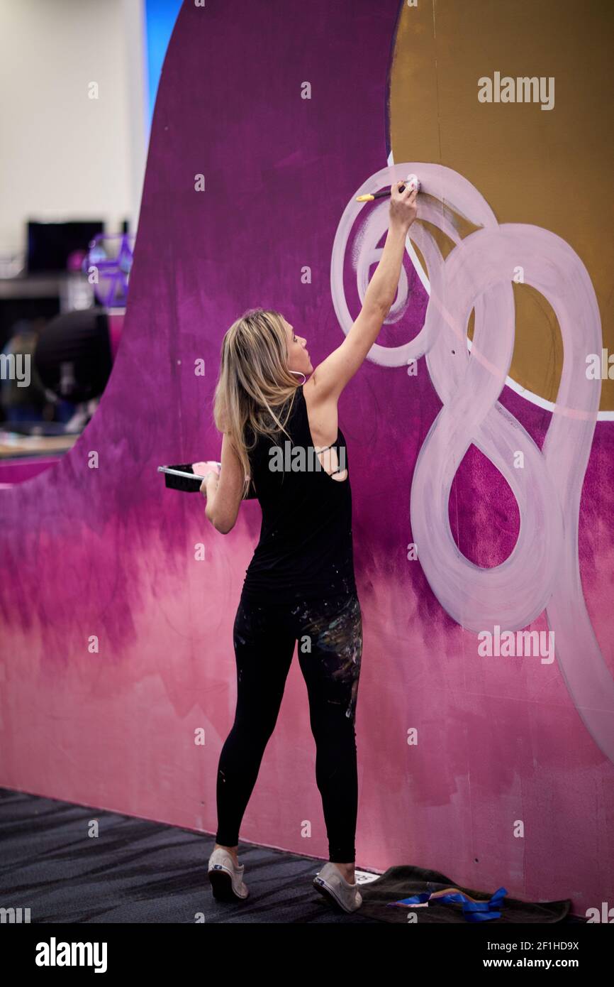 Female mural artist paints pink swirls at Musical Instrument Convention Stock Photo