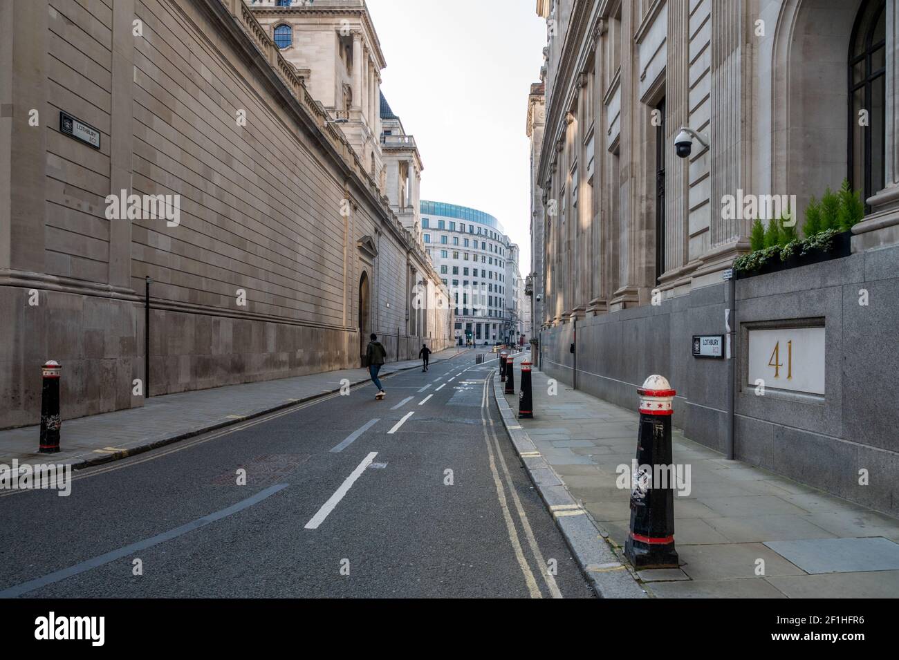 Covid pandemic lockdown; a deserted street in the City of London financial district with two skate borders. (Lothbury, Bank of England, London). Stock Photo