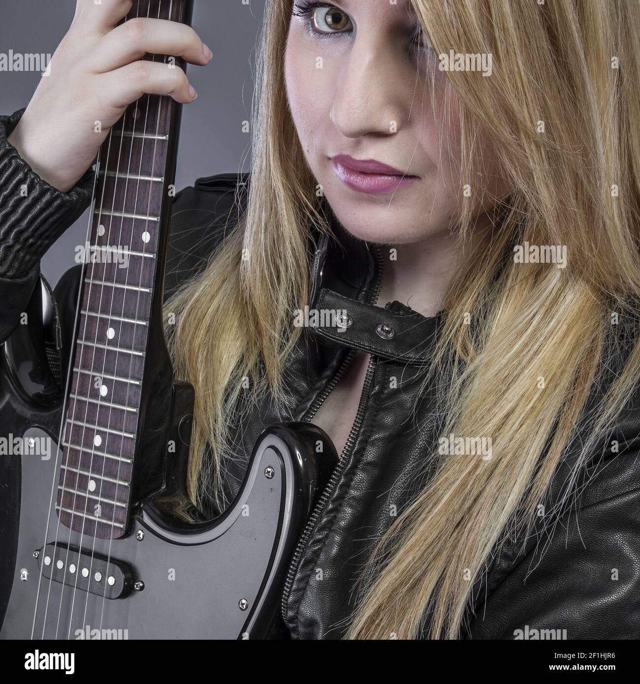 Beautiful blond girl with black electric guitar Stock Photo