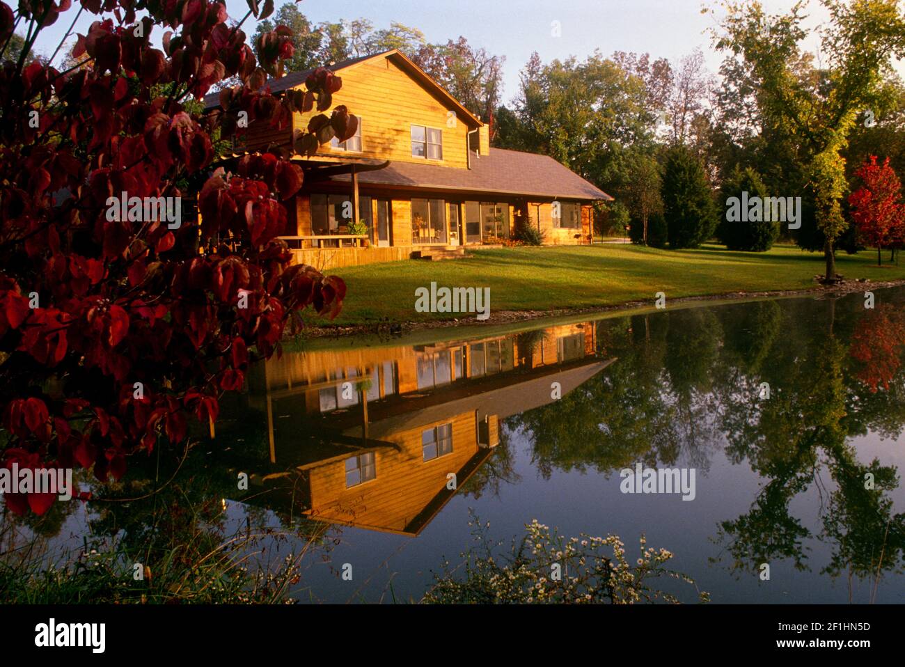 Lovely cedar house on a lake in fall with evening light reflected in the lake, Missouri, USA Stock Photo