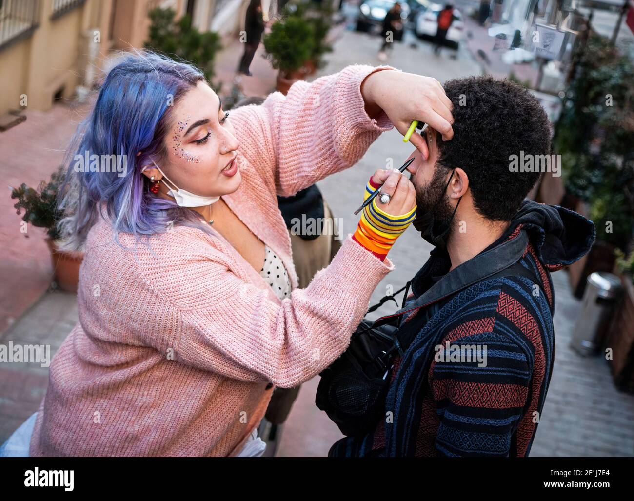 Istanbul, Turkey. 08th Mar, 2021. A woman is seen doing make up on a transwoman before the demonstration.Several people have gathered in Taksim with an intention to do a night parade in honour of International Women's Day, 8th March however due to the gathering restriction from the Istanbul Governor, local police stopped the group from carrying out the parade. In response this, the group has walked from Taksim to Karaköy while demonstrating their feminist opinions. Credit: SOPA Images Limited/Alamy Live News Stock Photo