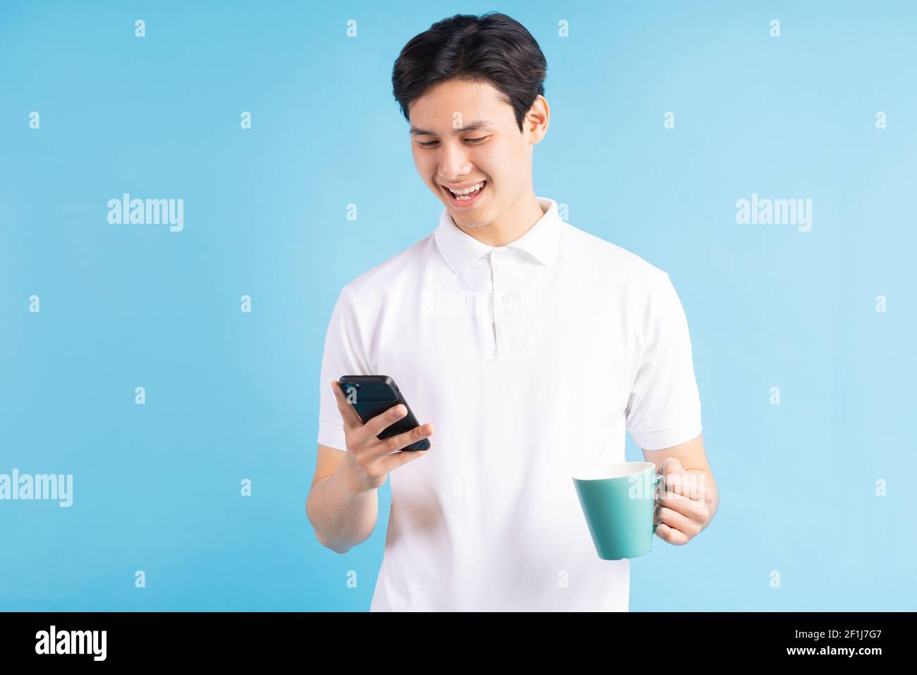a photo of a handsome Asian man texting while drinking water Stock Photo