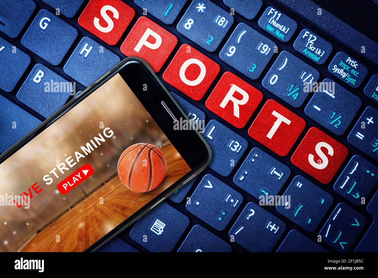 Sports Live streaming concept showing Basketball game broadcast on smartphone with laptop high tech background. Accessible on demand digital content i Stock Photo