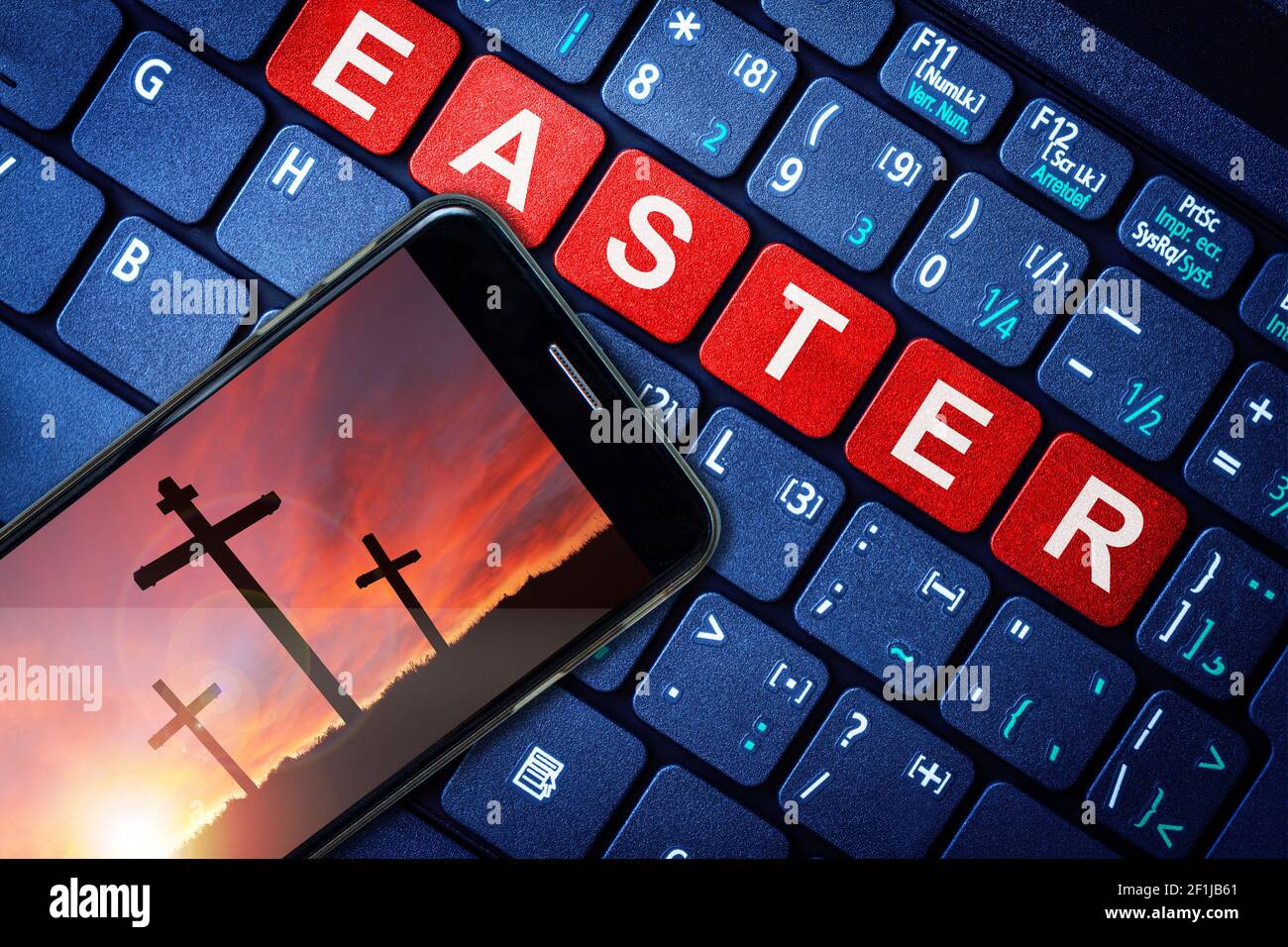 Smartphone showing symbol of Christian cross against a dramatic sunset on Good Friday or Easter Sunday. New Normal religious observance via online liv Stock Photo