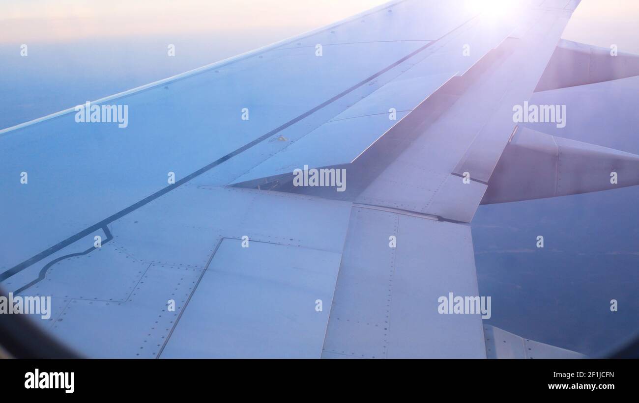 Airliner wing raises flaps to prepare for landing Stock Photo