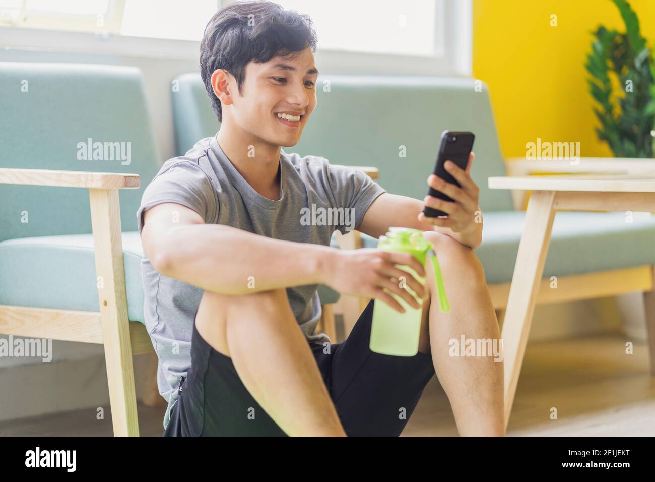 Asian man resting and using phone after exercising Stock Photo