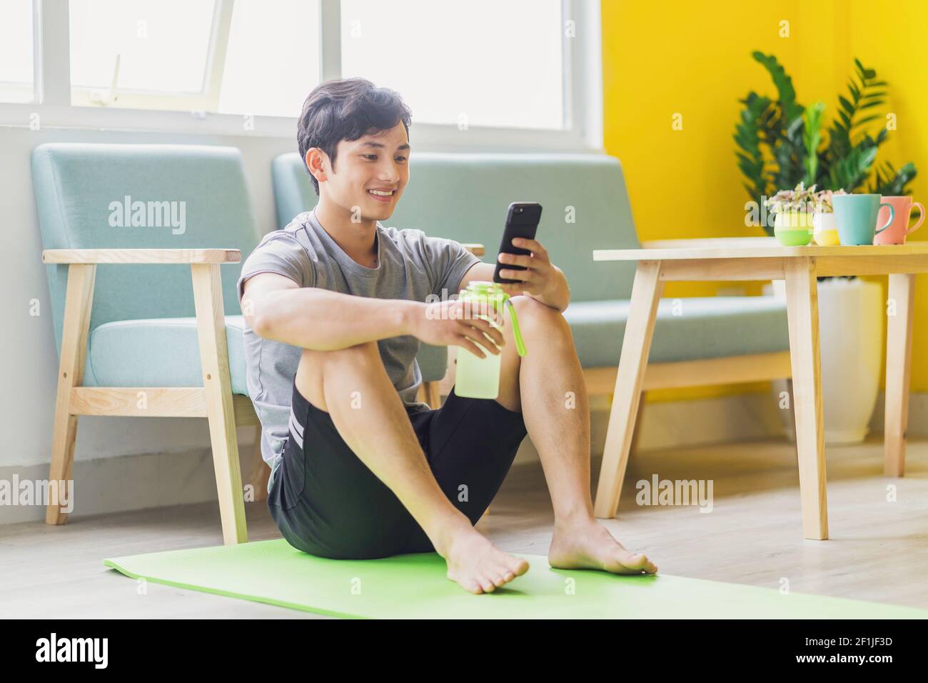 Asian man resting and using phone after exercising Stock Photo