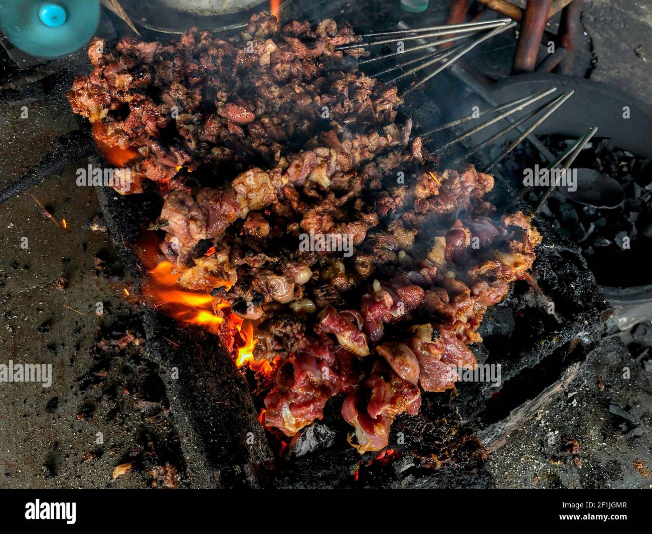 Goat satay on red fire grilling by people. traditional Indonesian food made from mutton. Stock Photo