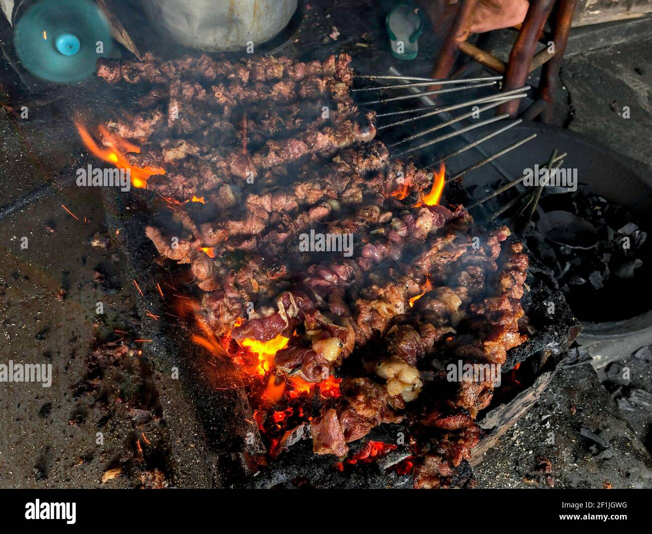 Goat satay on red fire grilling by people. traditional Indonesian food made from mutton. Stock Photo