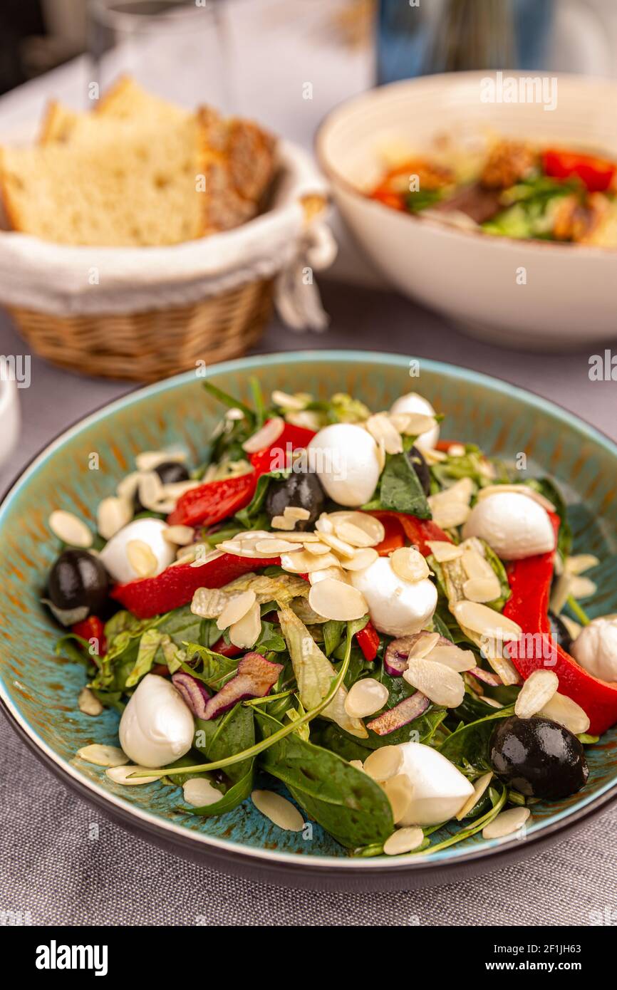 Plate of fresh lettuce salad with grilled red pepper mozzarella and olives Stock Photo