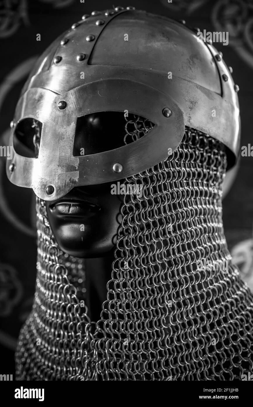 Soldier Viking helmet with chain mail of iron on red shield of wood and golden triskel Stock Photo