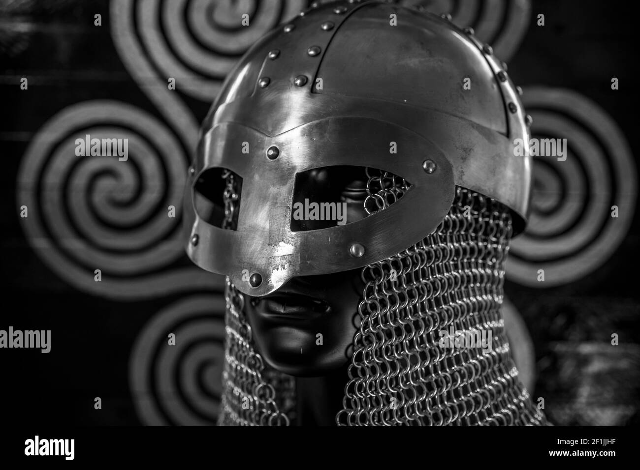 Viking helmet with chain mail of iron on red shield of wood and golden triskel Stock Photo