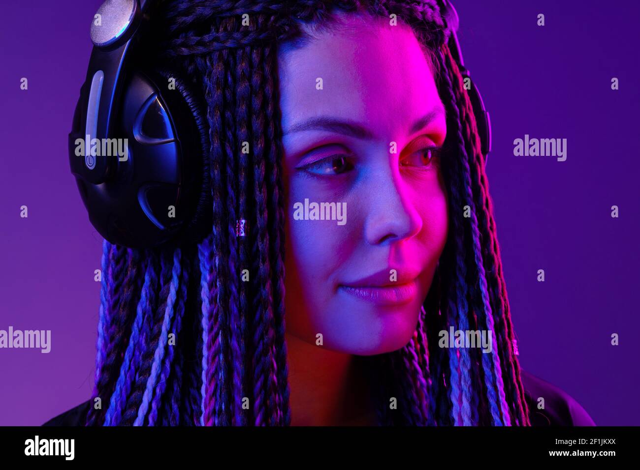 Beautiful woman with long hair in braids listening to music with ...