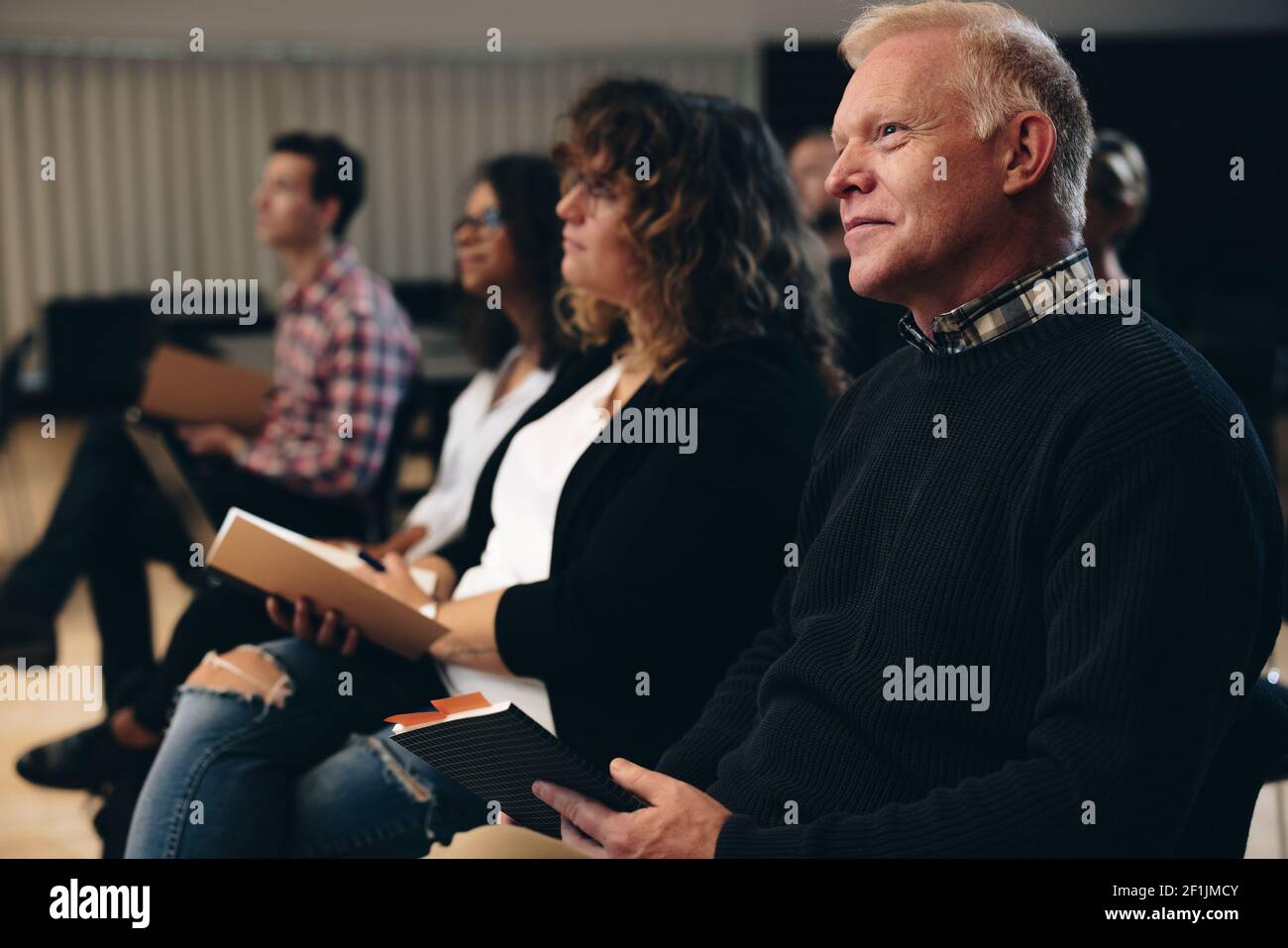 Senior man sitting in audience paying attention to the seminar. business people attending a corporate workshop. Stock Photo