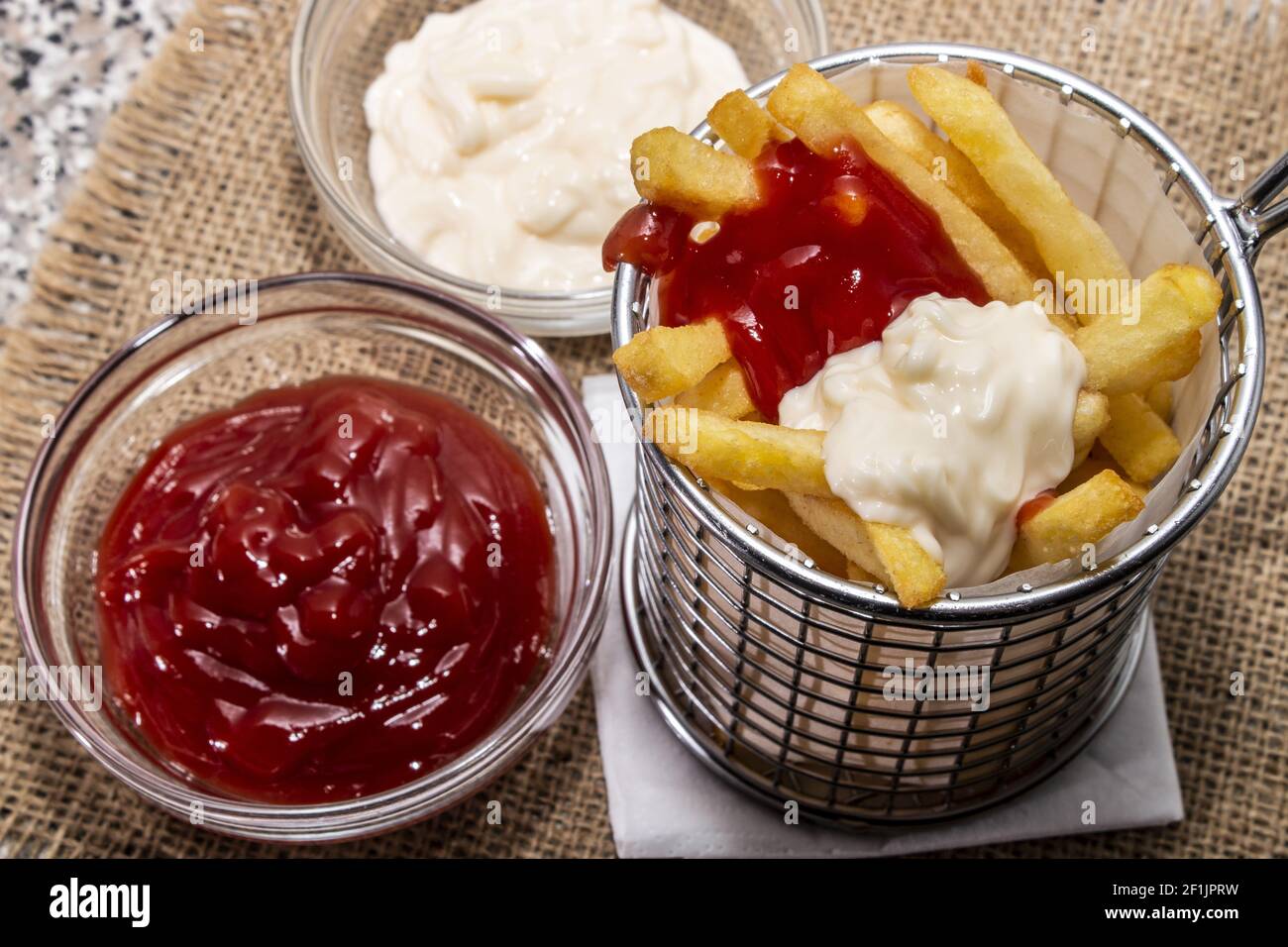 french fries red and white in a basket with ketchup and mayonnaise in a bowl Stock Photo