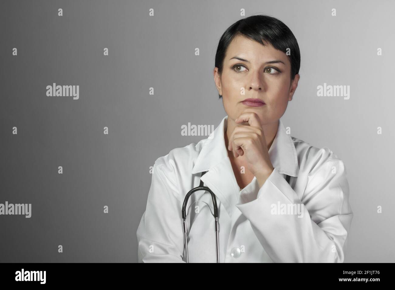 Portrait of an attractive young female doctor in white coat. Smiling medical woman doctor. Isolated over white background Stock Photo