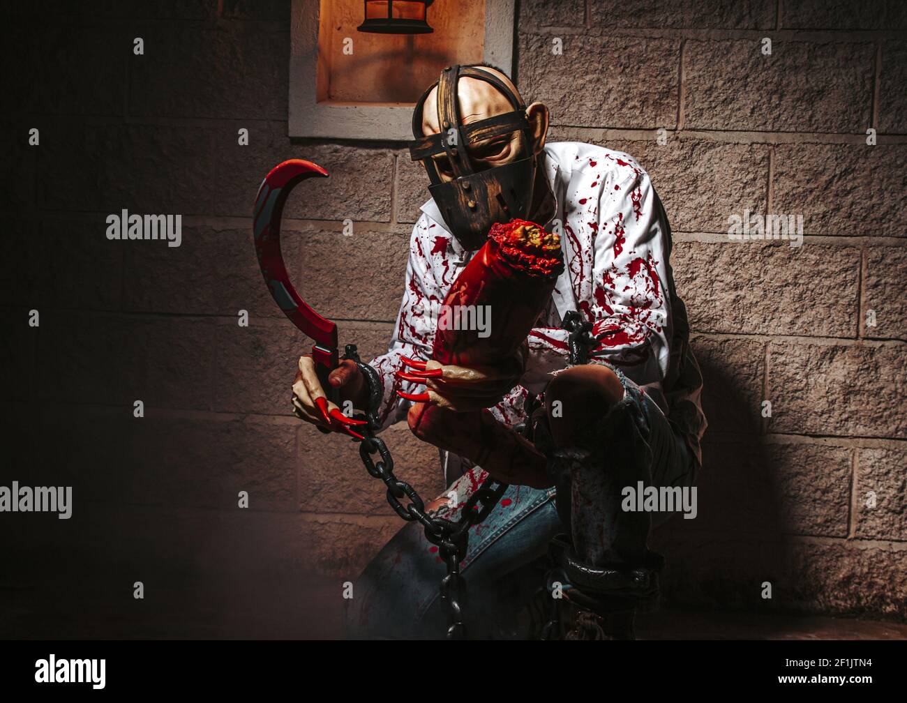 Halloween holiday celebration, cosplay. Man demon on castle background. Satan with chains, red blood. Hell, death, evil, horror Stock Photo