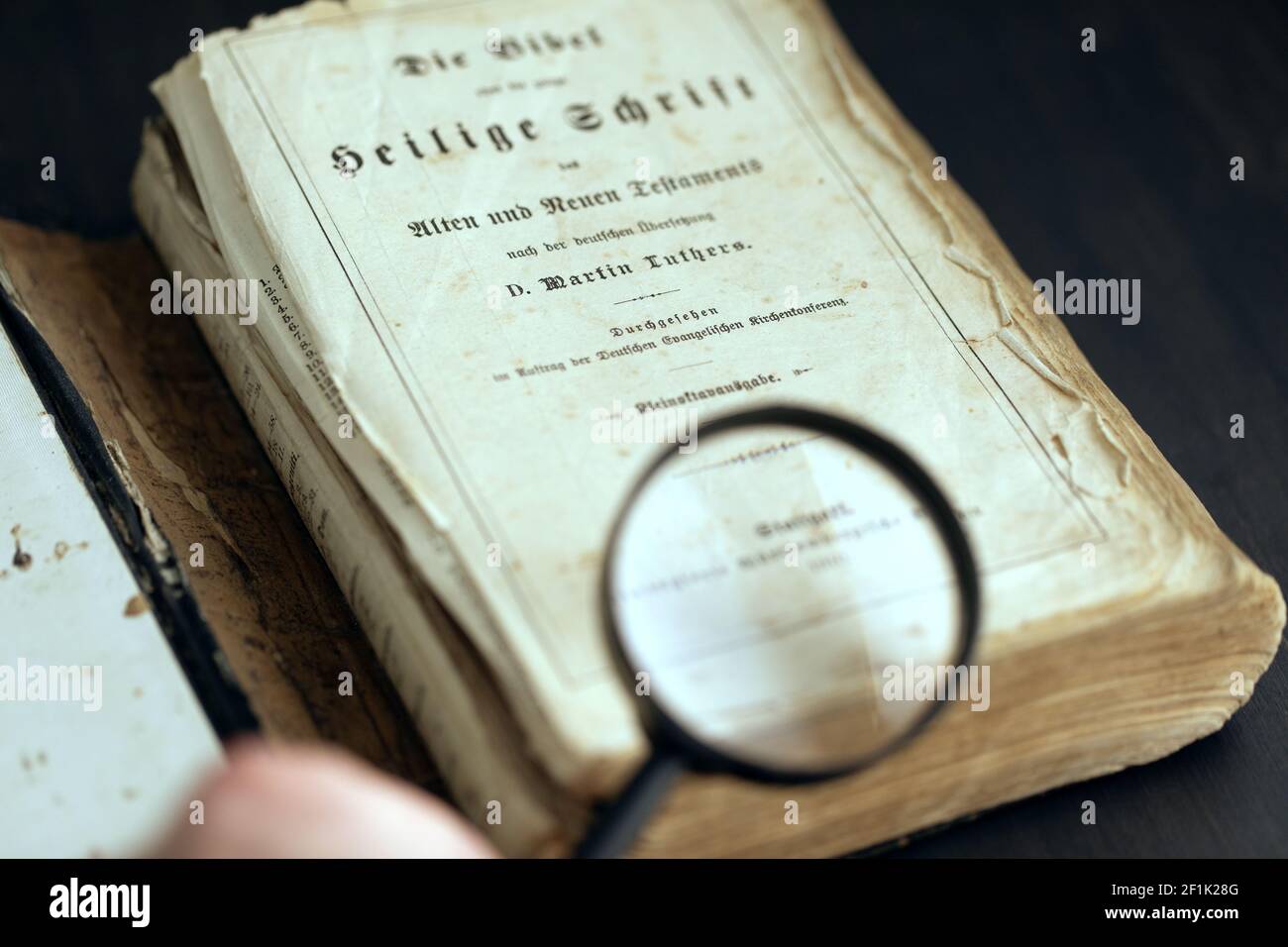 Vintage old historic paper text book opened on table and magnifying ...
