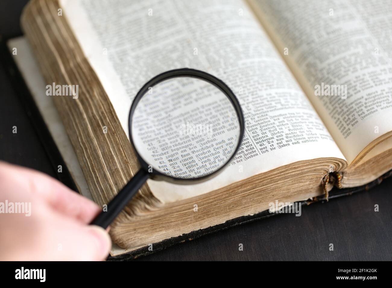 Vintage old historic paper text book opened on table and magnifying