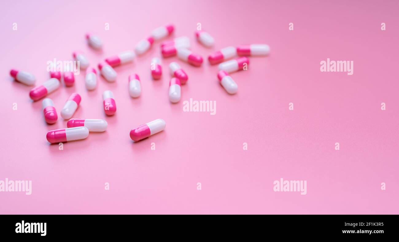 Pink-white antibiotic capsules pill spread on pink background. Pharmacy banner. Antibiotic resistance concept. Pills and love concept. Pharmaceutical Stock Photo