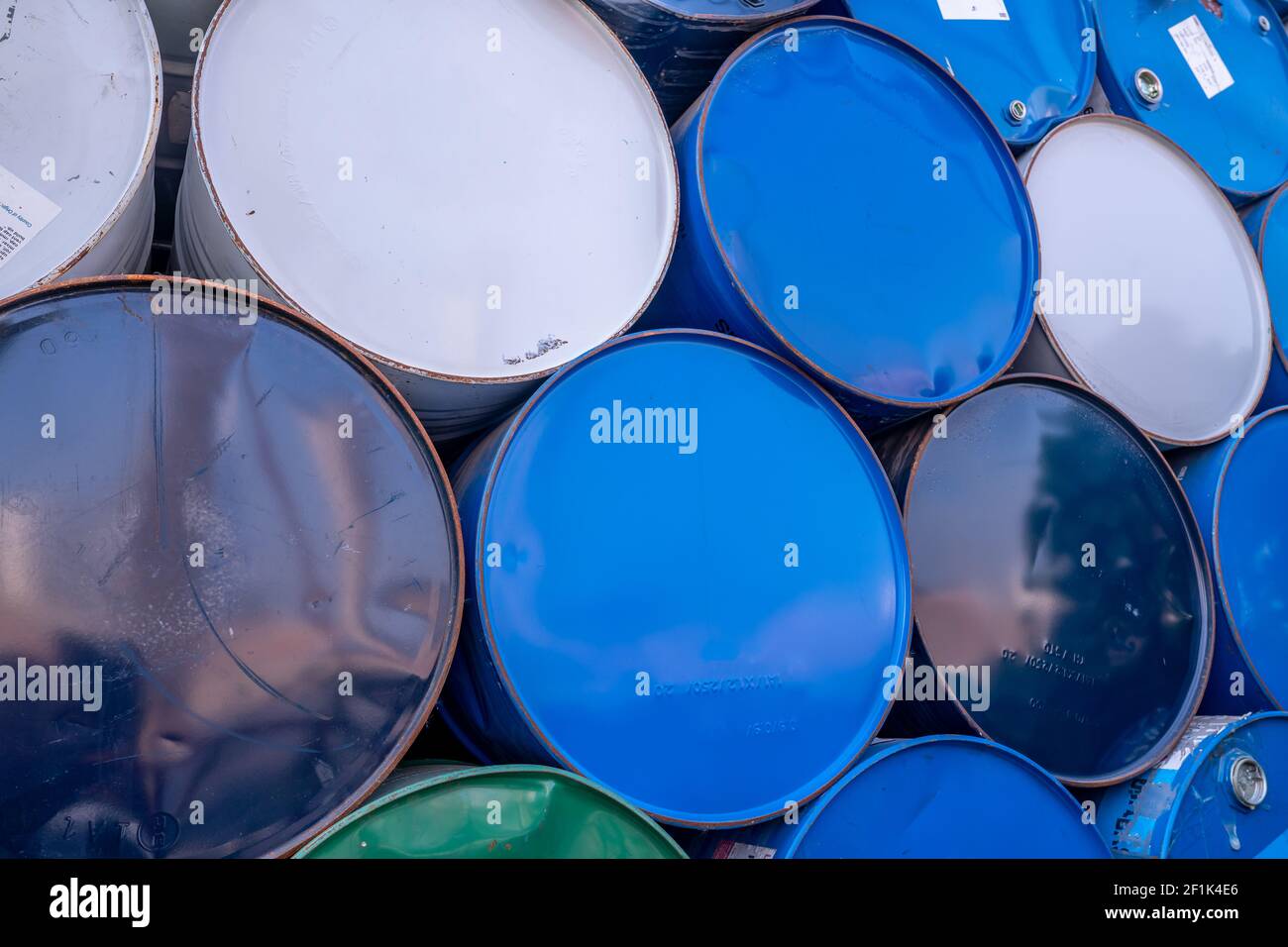 Old chemical barrels. Blue, white, and green oil drum. Steel oil tank. Toxic waste warehouse. Hazard chemical barrel. Industrial waste in old drum. Stock Photo