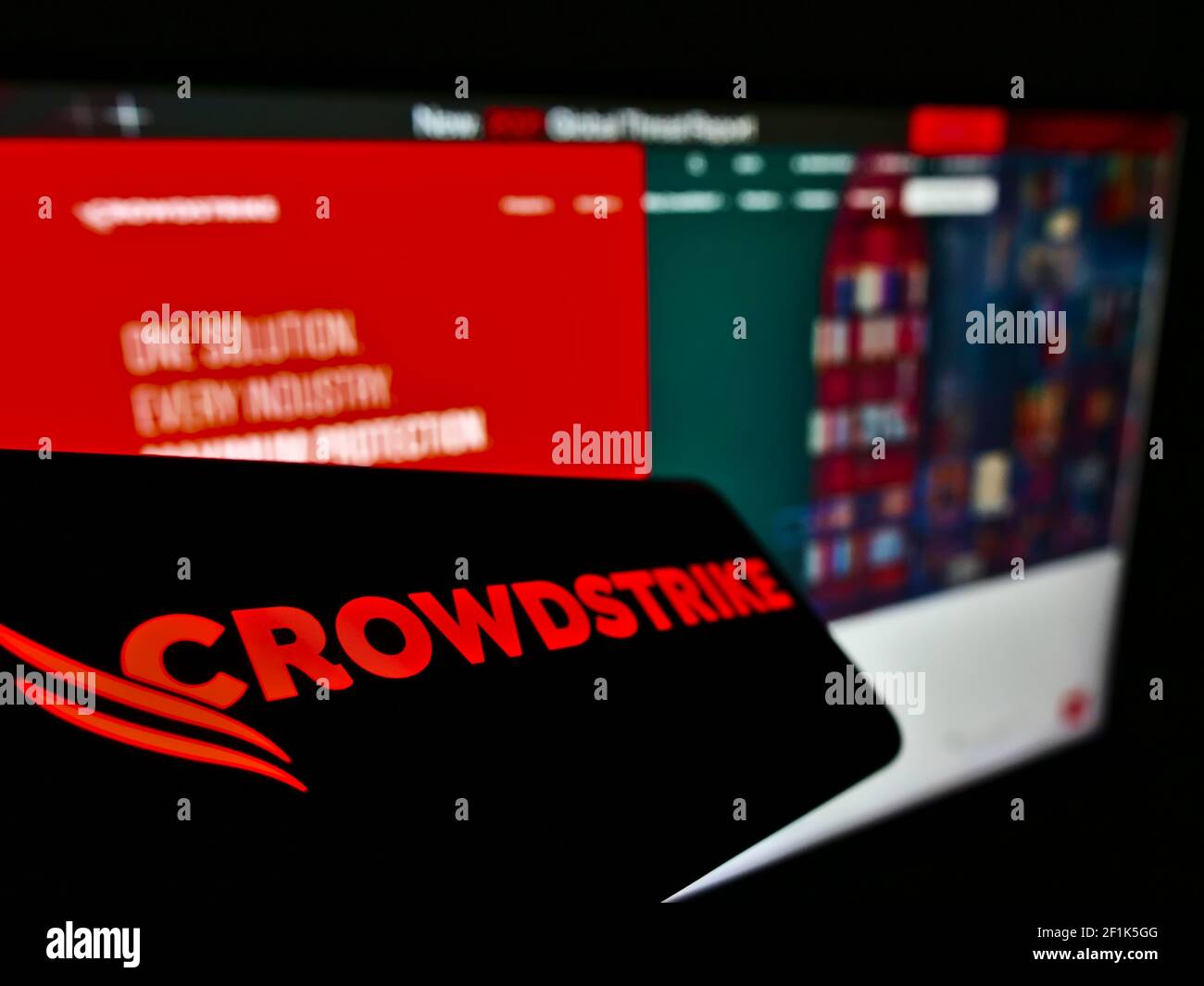 Mobile phone with logo of US cyber security company CrowdStrike Holdings Inc. on screen in front of web page. Focus on center-left of phone display. Stock Photo