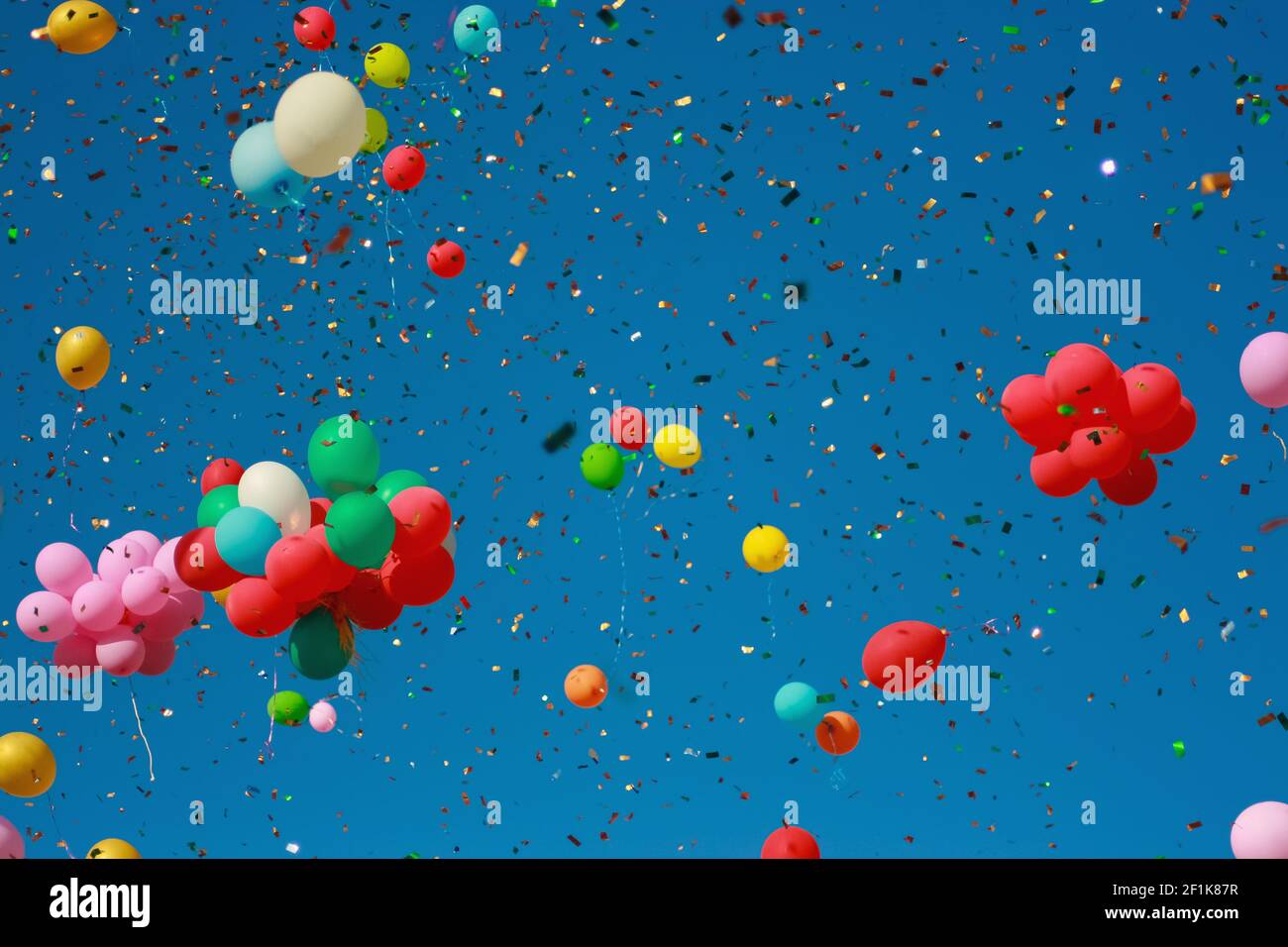 Multicolored glitter balloons launched into the blue sky. Celebration, birthday, balloons with helium. Stock Photo