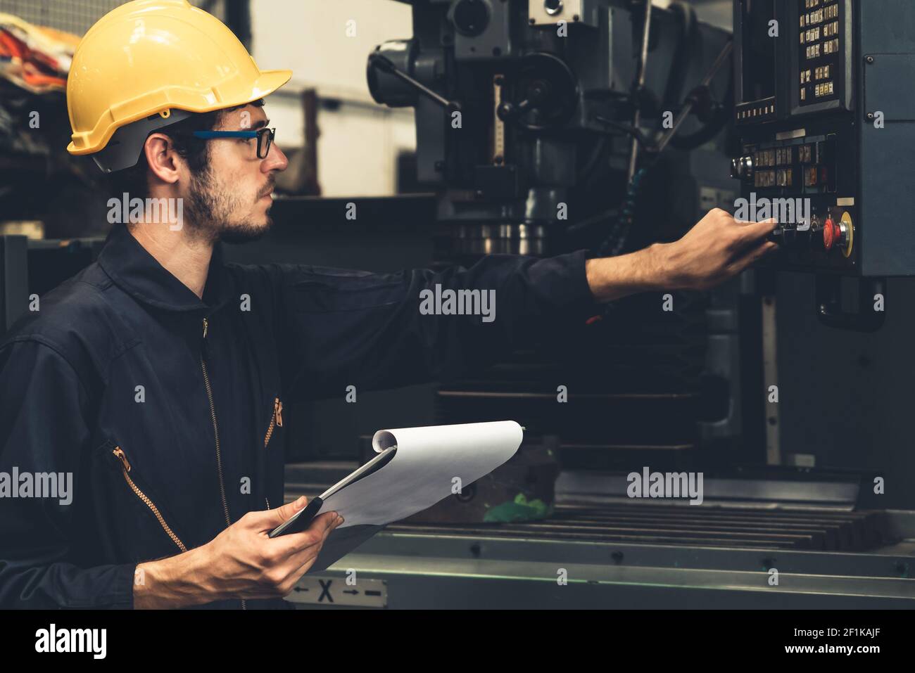 Skillful factory worker working with clipboard to do job procedure