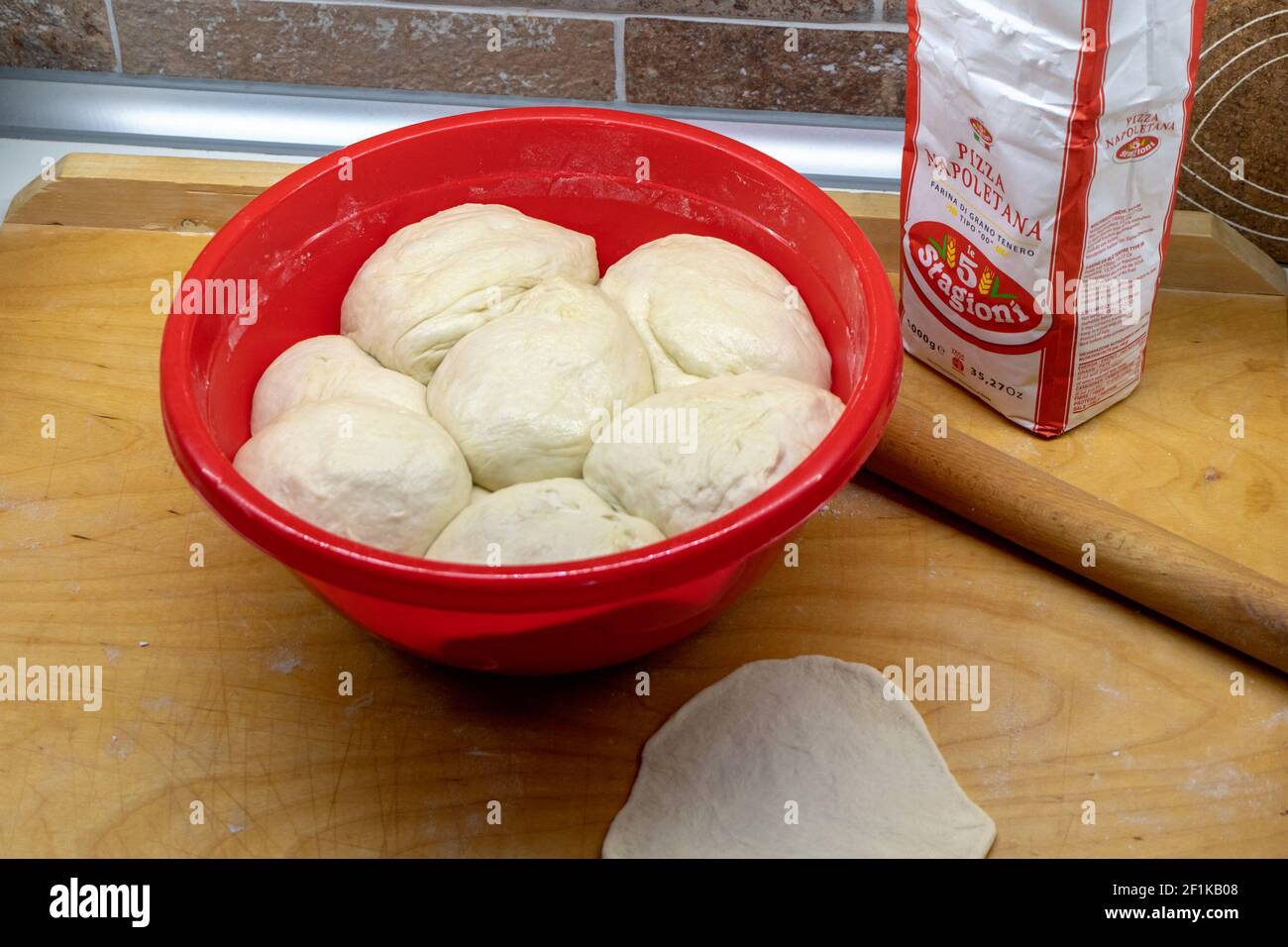 Illustrative editorial, home made pizza dough in a red plastic bowl and a paper bag with special italian flour Stock Photo