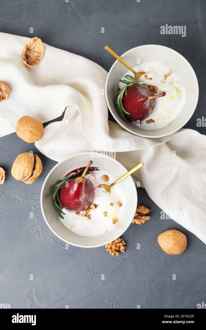 Bowls with sweet poached pears in red wine and icecream on dark