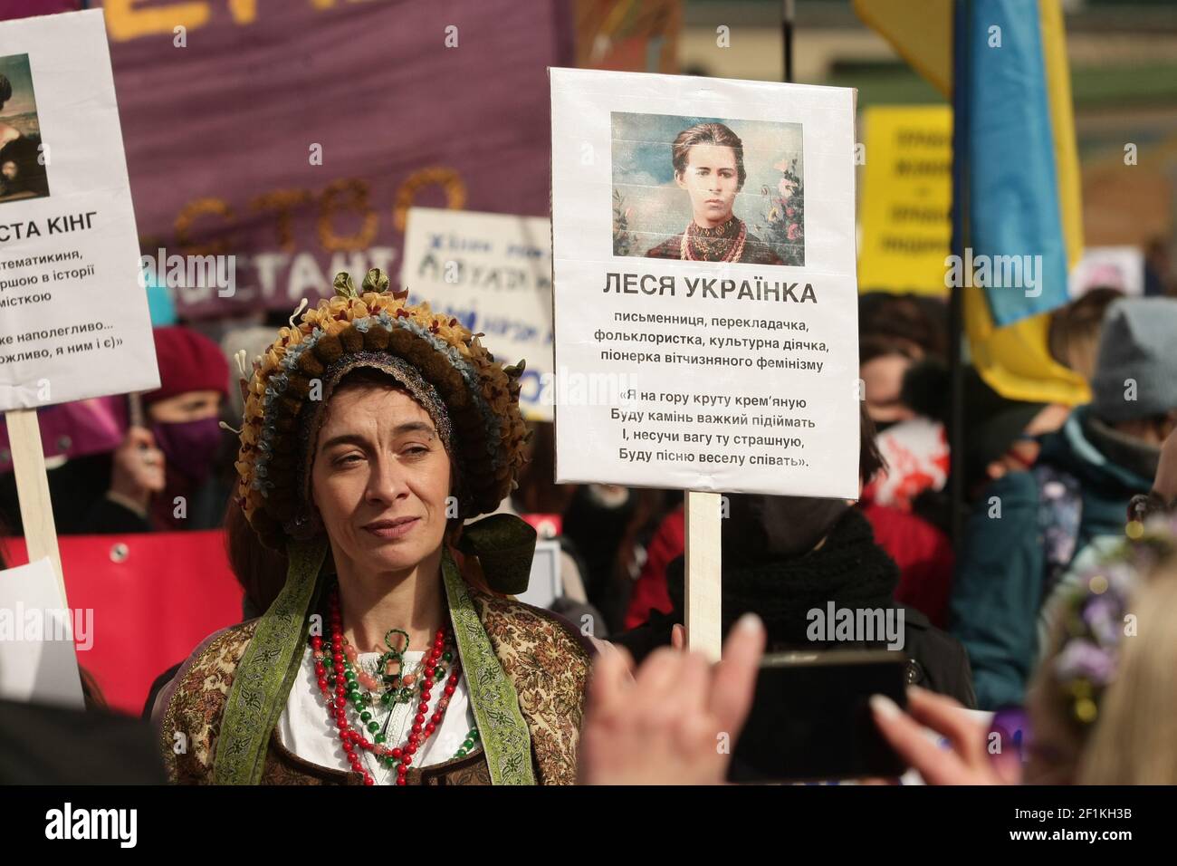 KYIV, UKRAINE - MARCH 8, 2021 - A woman in a period costume holds a placard featuring Ukrainian writer Lesya Ukrainka as participants gather for the M Stock Photo