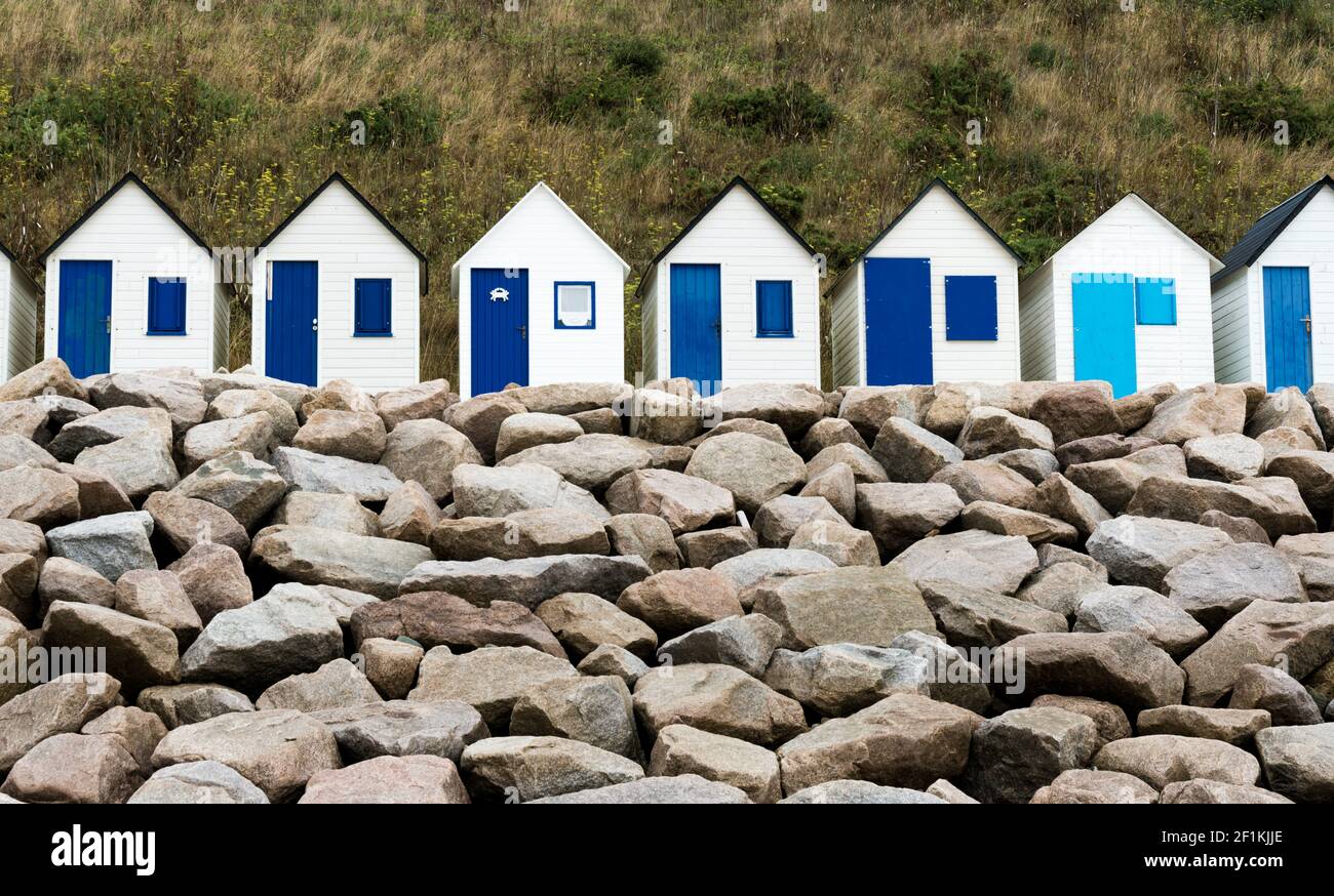 Row of small wooden beach cottages on the rocky Normandy coast Stock