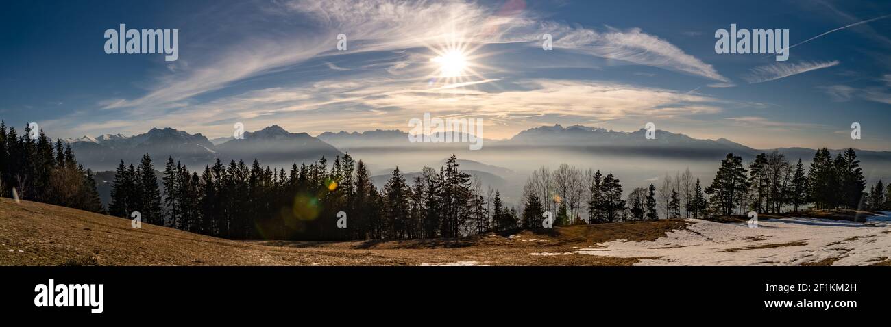 Panorama with the Rhine valley and the Swiss mountain range Alpstein and Säntis. colored afterglow und sunset with veil clouds and row of trees, snowy Stock Photo