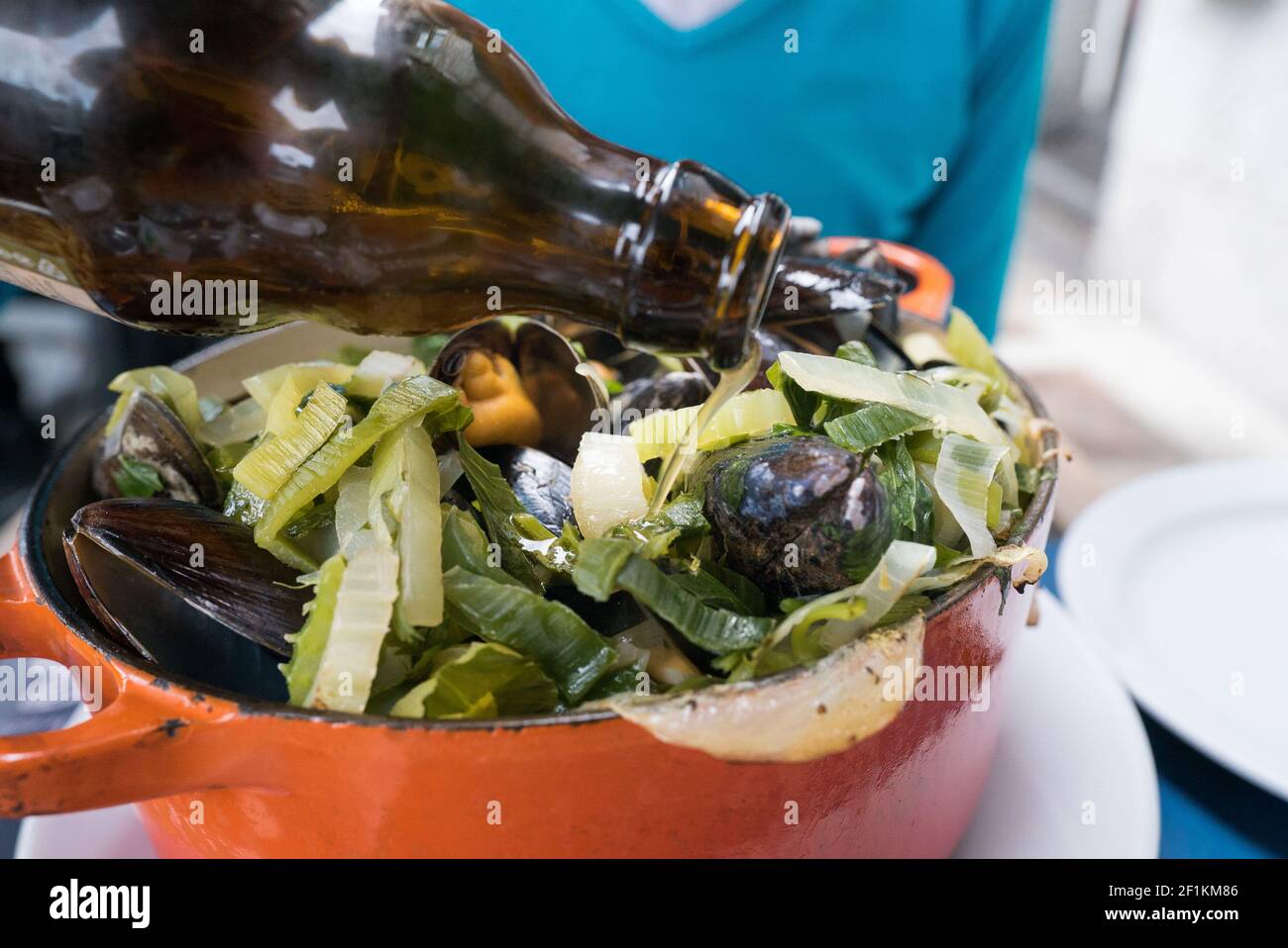 Pouring beer over traditional mussel and french fries dish called
