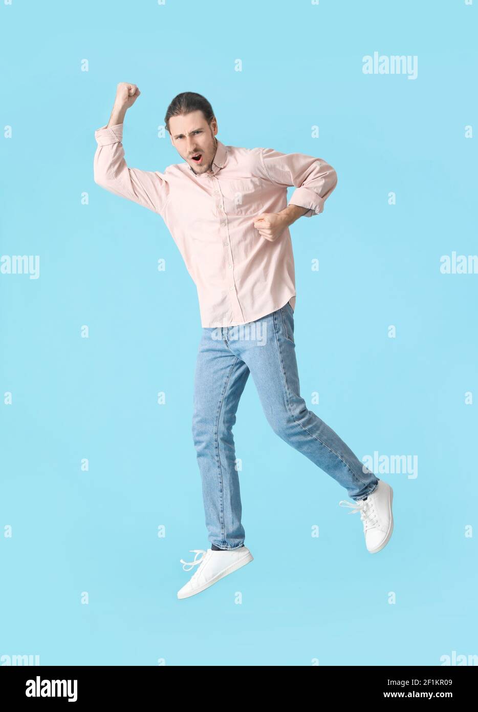 Jumping young man against color background Stock Photo