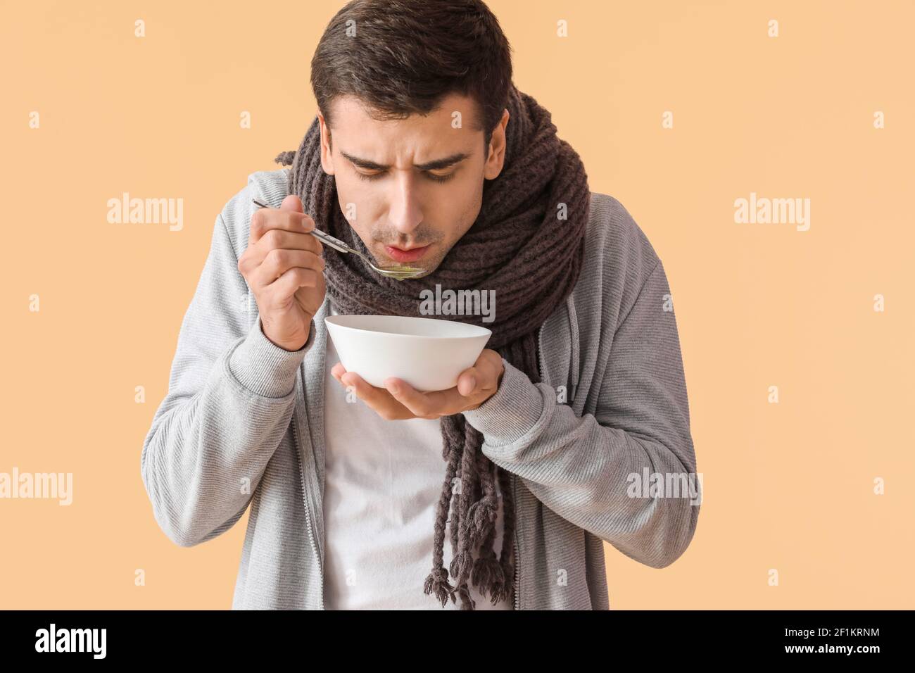 Sick man eating chicken soup on color background Stock Photo Alamy