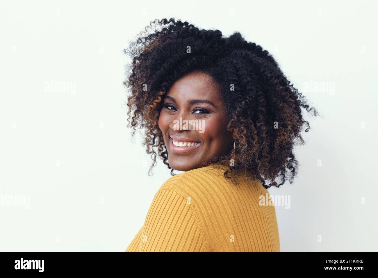 Portrait of happy beautiful young woman with curly hair wearing yellow ...