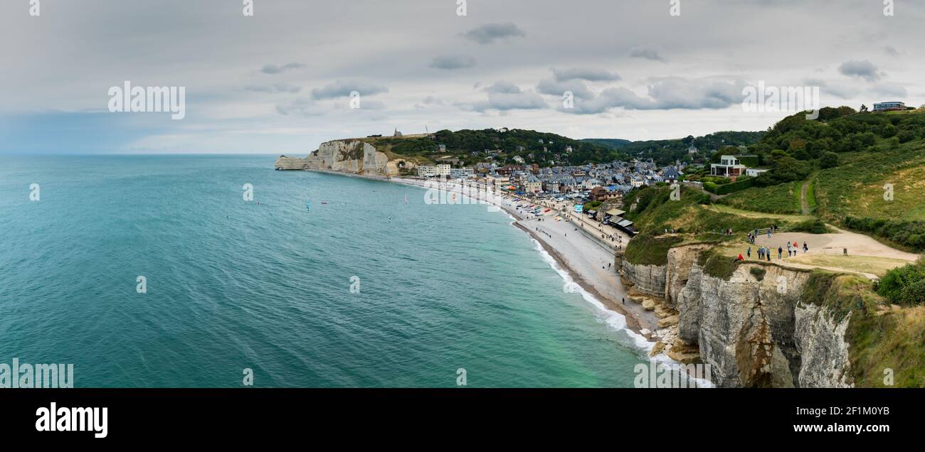Tourists enjoy hiking on the Normandy coast along the Falaise de Etretat cliffs above the village of Stock Photo
