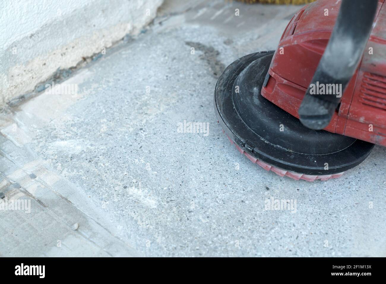 Construction worker uses a concrete grinder for removing tile glue
