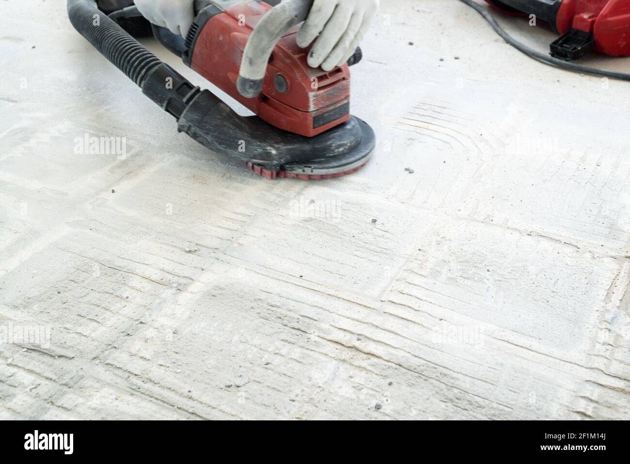 Construction worker uses a concrete grinder for removing tile glue and