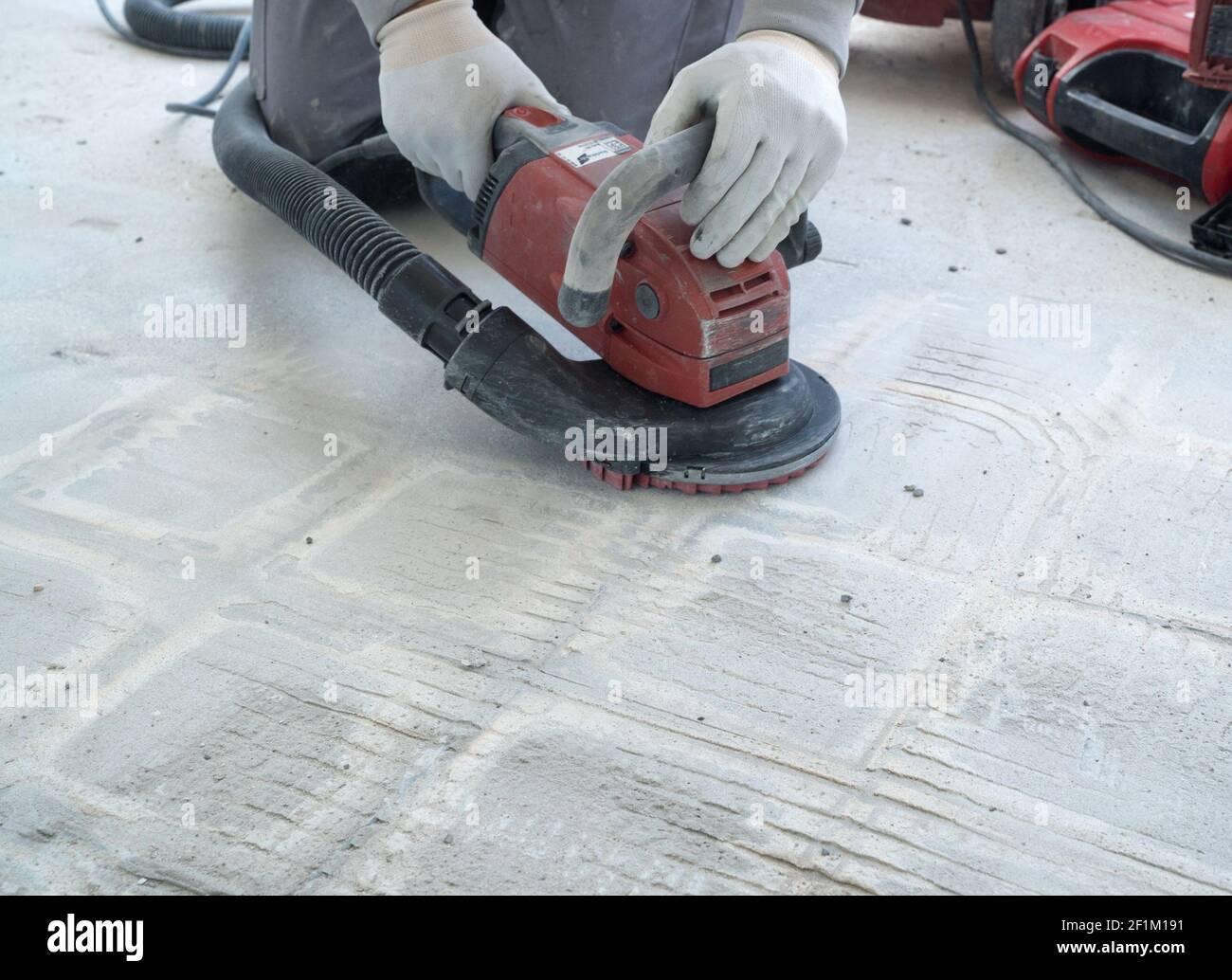 Construction worker uses a concrete grinder for removing tile glue and