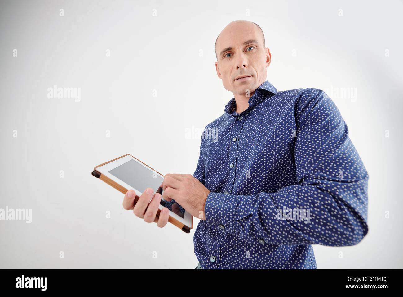 Portrait of handsome serious mature man standing with tablet computer in hands Stock Photo