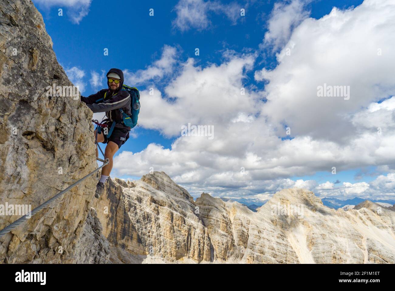 Young male mountain climber on a steep and exposed rock face climbing a Via Ferrata Stock Photo