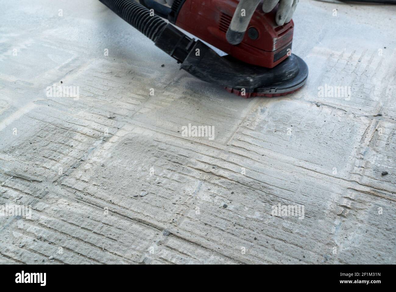 Construction worker uses a concrete grinder for removing tile glue and