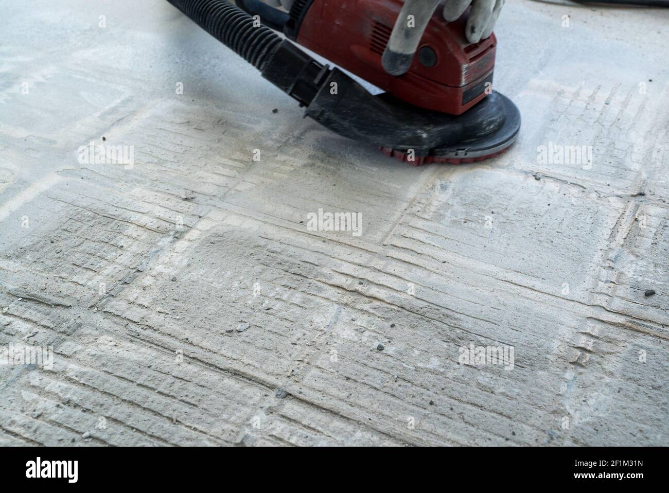 Construction worker uses a concrete grinder for removing tile glue and  resin during renovation work Stock Photo - Alamy
