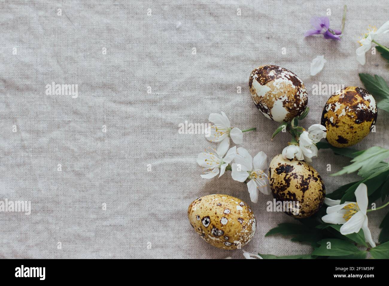 Easter eggs with spring flowers on rustic linen background, flat lay ...